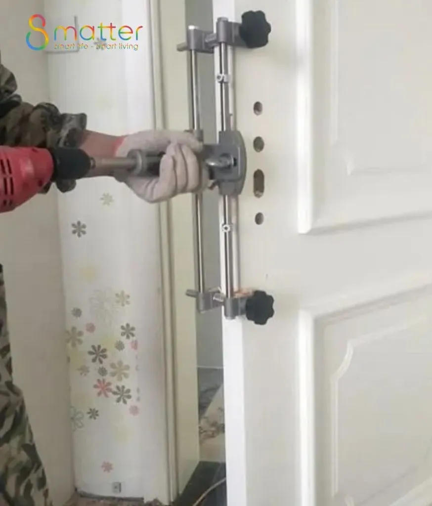 Thợ đeo găng dùng máy khoan đỏ cùng đồ gá inox để khoét lỗ định vị