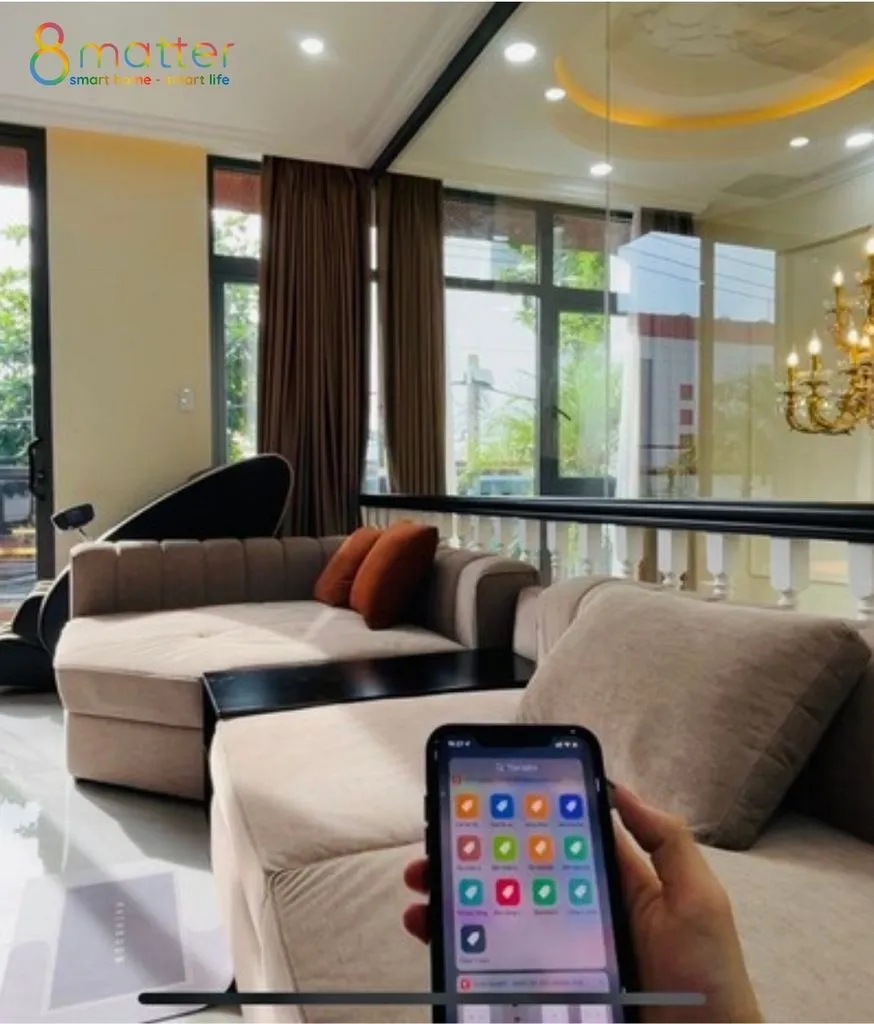 Phòng khách sang trọng, bàn tay cầm điện thoại mở app điều khiển nhiều nút