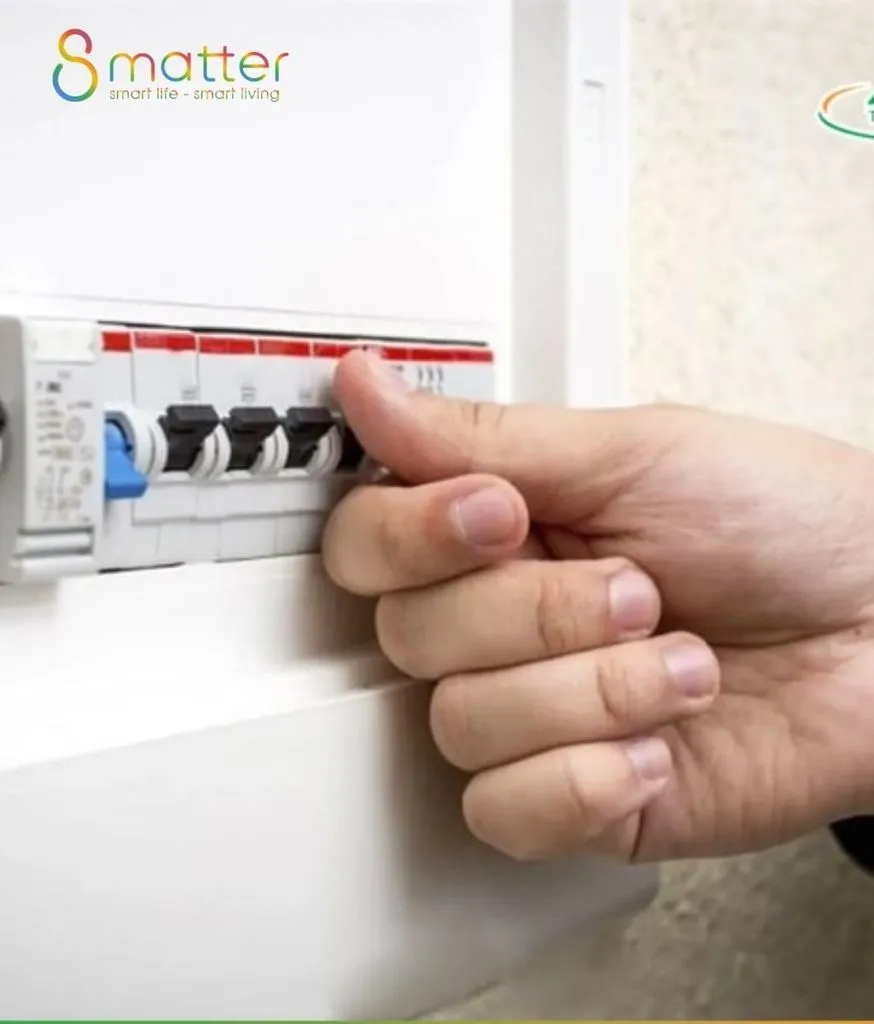 Bàn tay thao tác trên chiếc aptomat gắn trong tủ điện