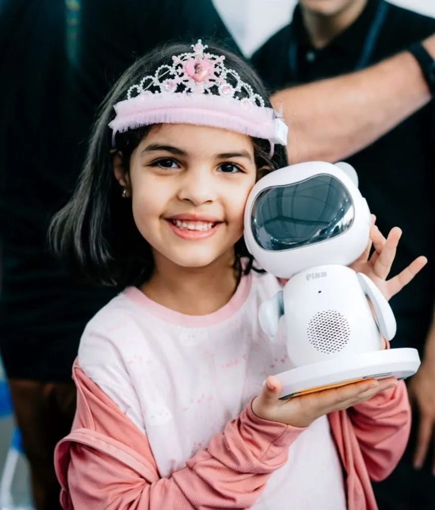 Bé gái đội vương miện cầm robot Pika bằng hai tay trong gian hàng trưng bày