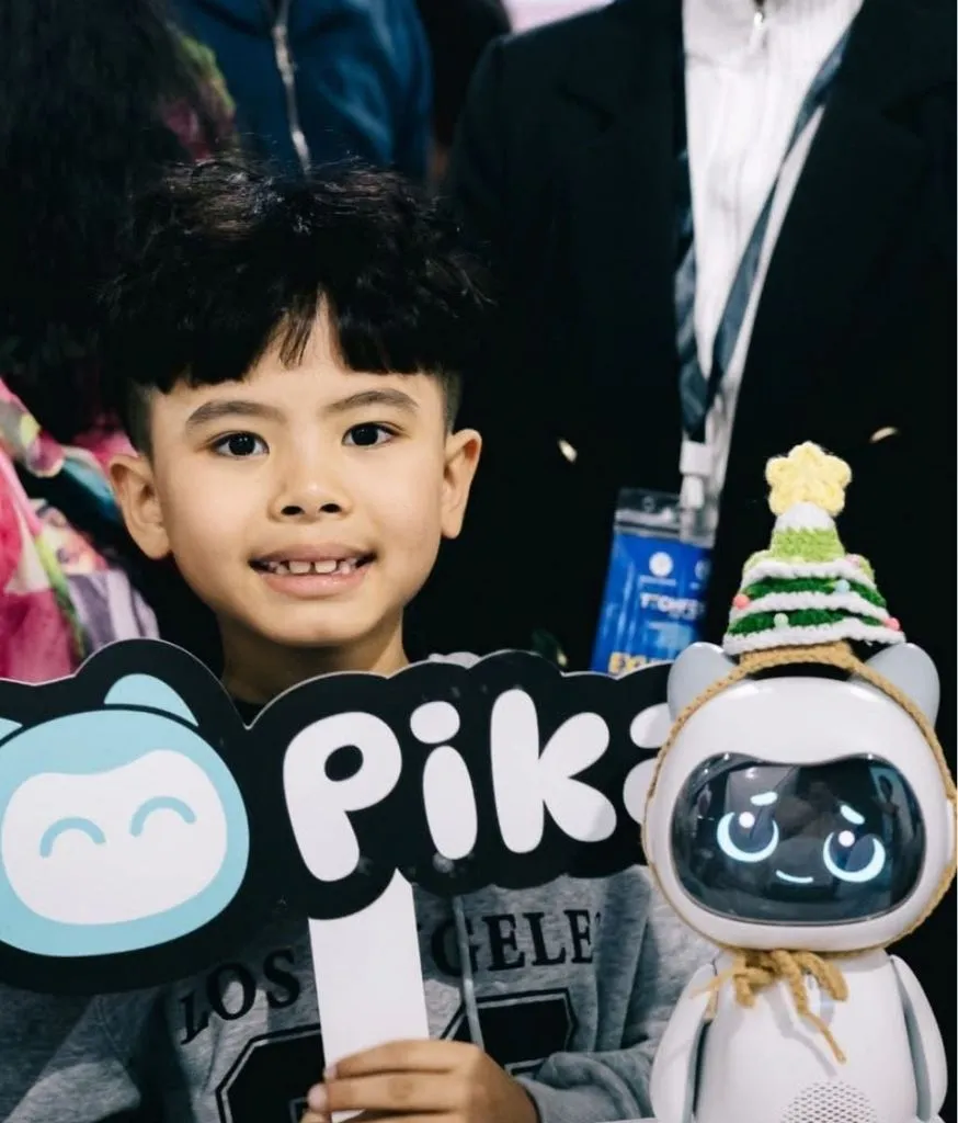 Bé trai cầm robot Pika đội mũ len trong khu vực trưng bày sản phẩm