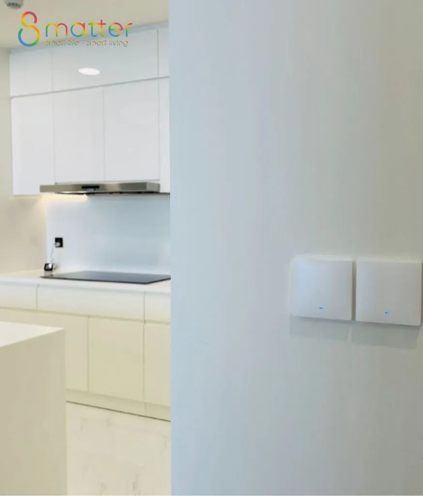 Gian bếp trắng hiện đại có máy hút mùi và công tắc trên tường