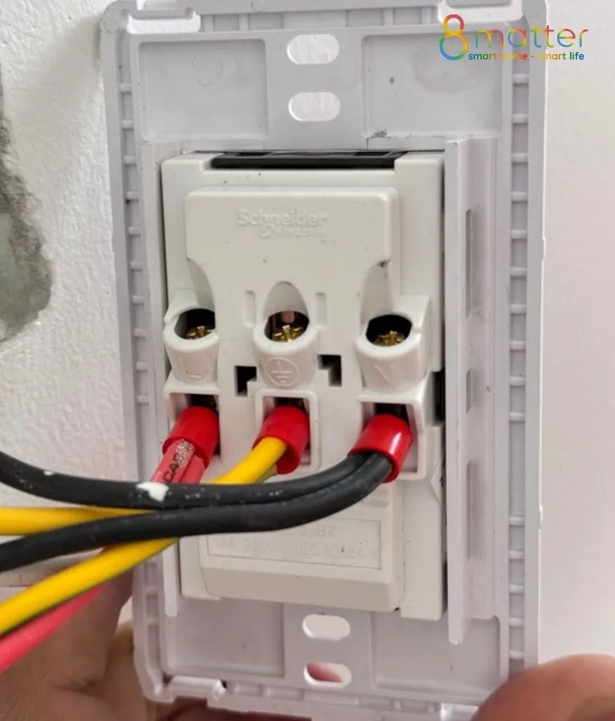 Mặt sau bộ ổ cắm đang được đấu các dây điện đỏ, vàng, đen vào cọc