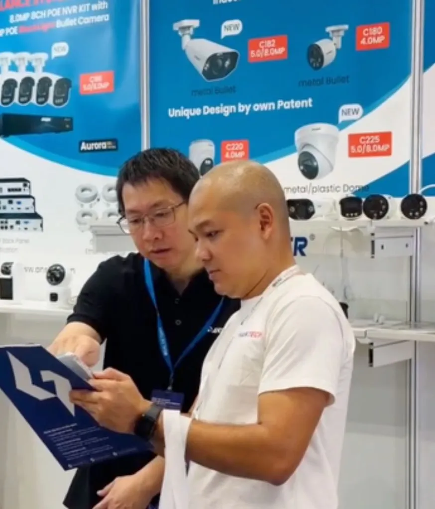 Hai người đàn ông xem tờ rơi trước gian hàng trưng bày camera an ninh