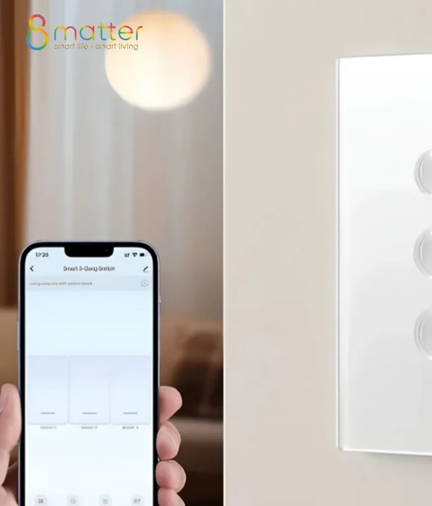 Bàn tay cầm điện thoại mở app công tắc ba nút, bên cạnh là công tắc mặt trắng gắn tường