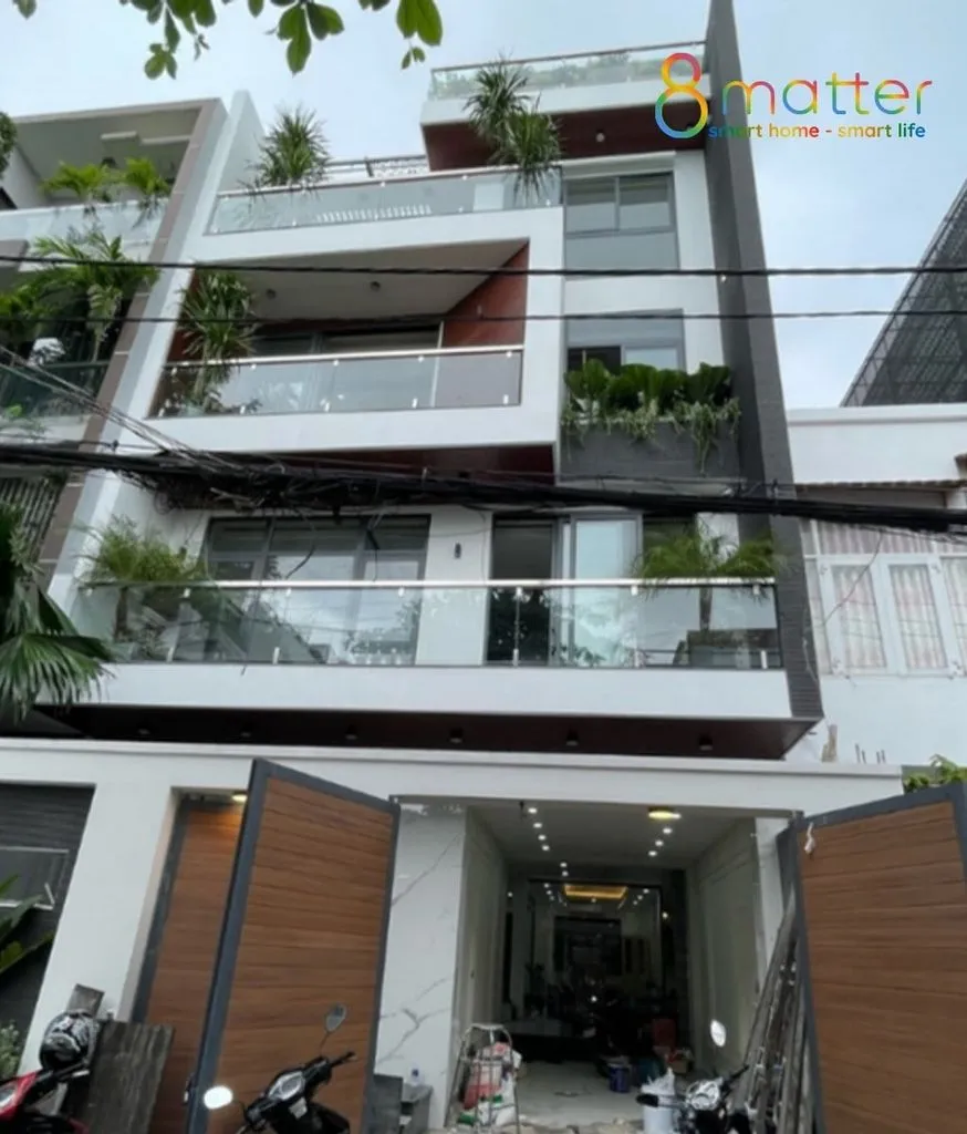 Nhà phố bốn tầng mặt tiền lan can kính, nhiều cây xanh ở ban công