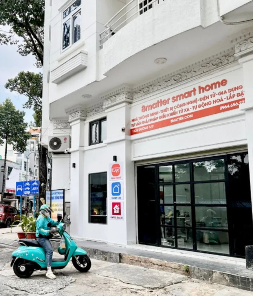 Cửa hàng 8matter Smart Home mặt tiền trắng, cô gái chạy xe máy ngang qua