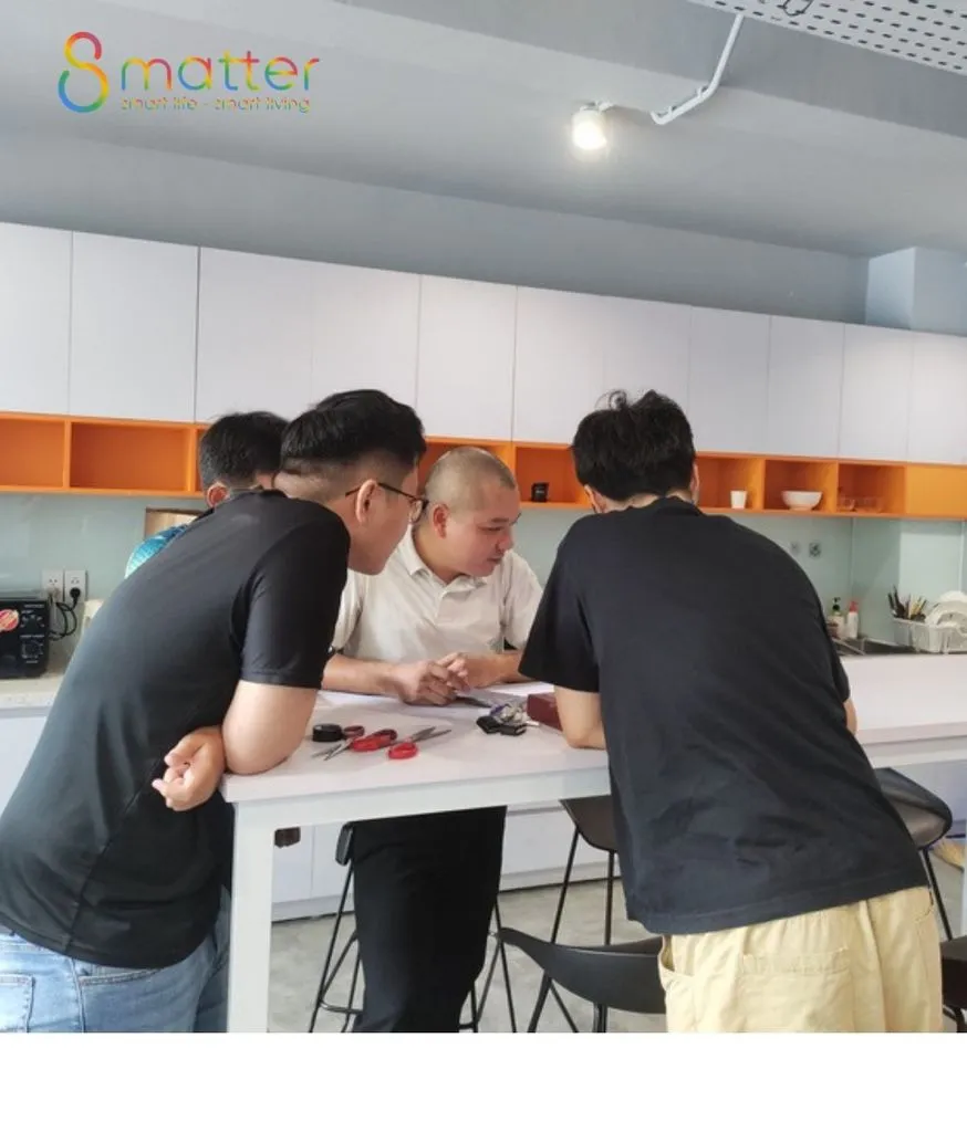 Bốn người đàn ông chụm đầu quanh bàn đảo bếp trắng xem linh kiện