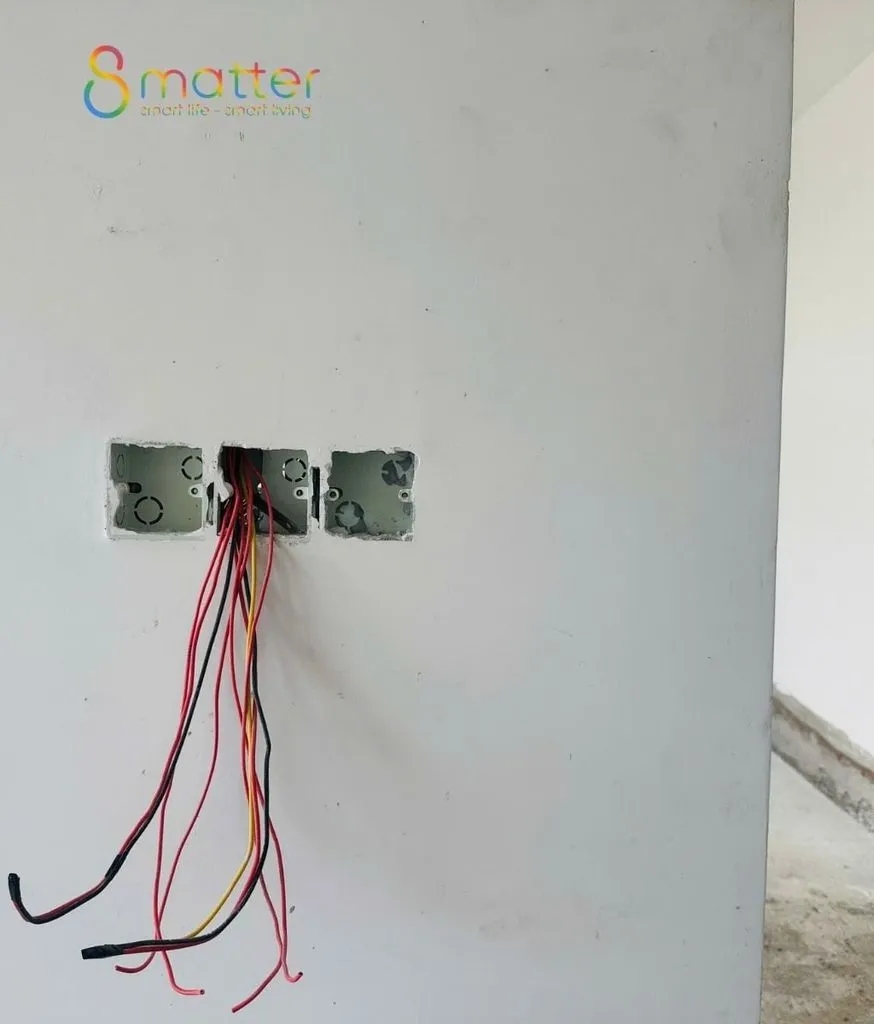 Đế âm tường lộ mấy sợi dây điện màu đỏ trên mảng tường chưa sơn
