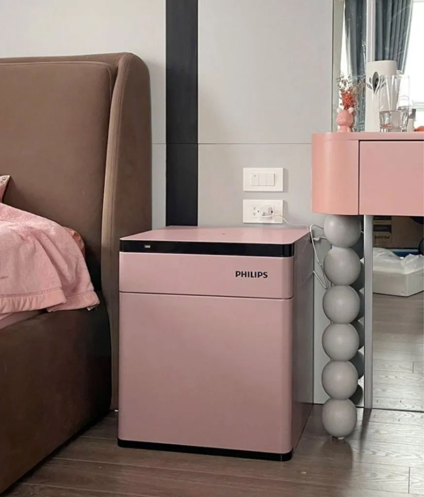 Két sắt màu hồng đặt cạnh giường ngủ và bàn trang điểm