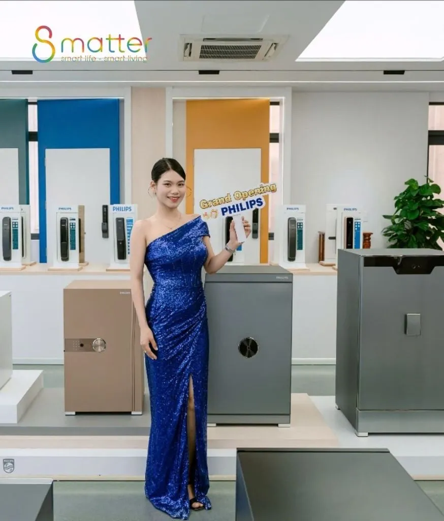 Người phụ nữ mặc váy xanh đứng cạnh hai chiếc két Philips trong showroom