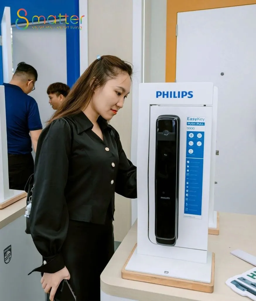 Khách nữ đứng xem chiếc khóa Philips trưng bày trên bục tại cửa hàng