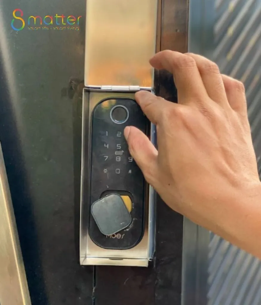 Bàn tay bấm bàn phím khoá cổng đen lắp trong hộp inox trên cổng sắt ngoài
