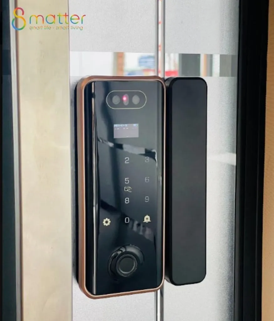 Khoá cửa đen viền đồng có camera gắn trên cửa nhôm kính phản chiếu ngoài trời