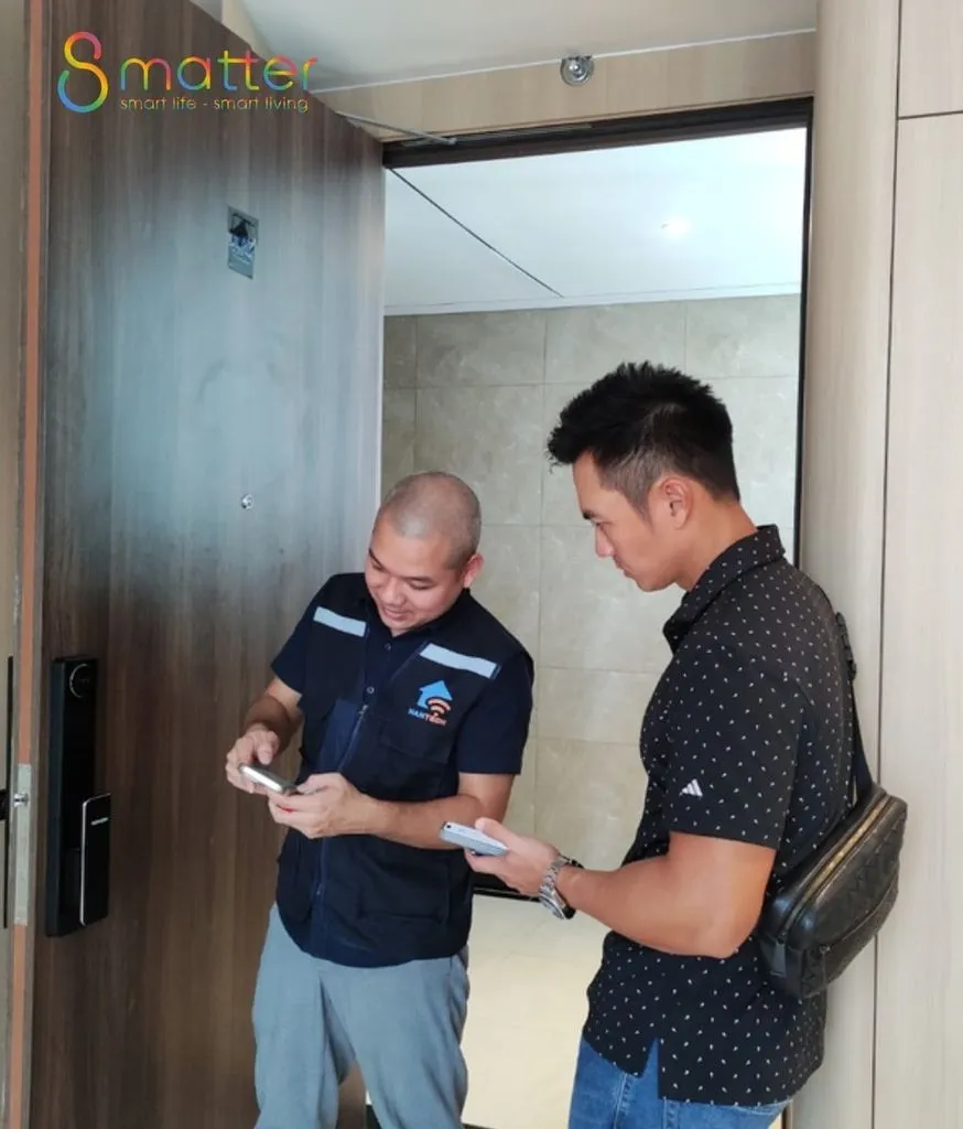 Hai người đàn ông đứng ở khung cửa gỗ cùng xem thiết bị nhỏ