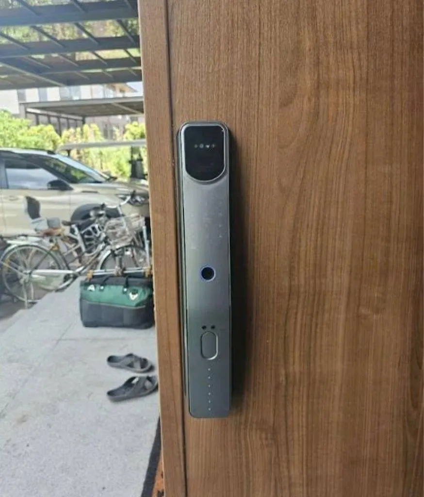 Khoá đẩy màu tối trên cửa gỗ, ngoài sân có xe đạp và dép