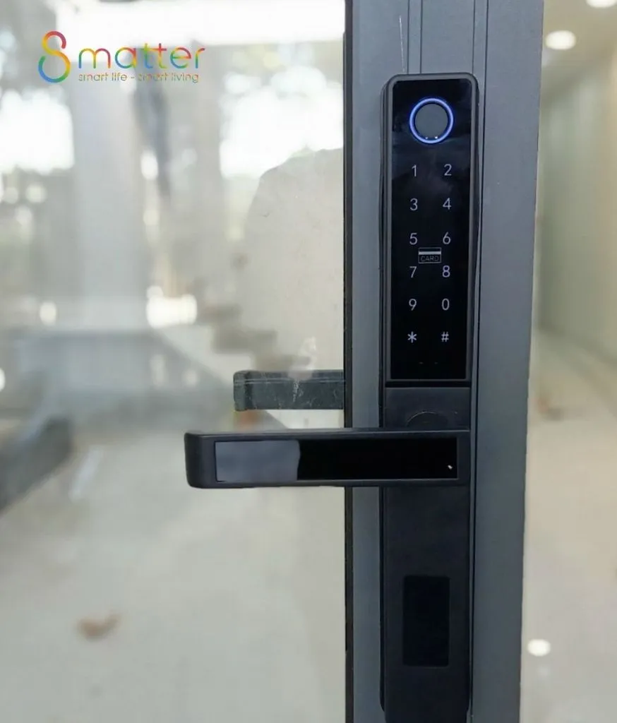 Khóa cửa thông minh đen có màn hình tròn màu xanh gắn trên cánh cửa kính
