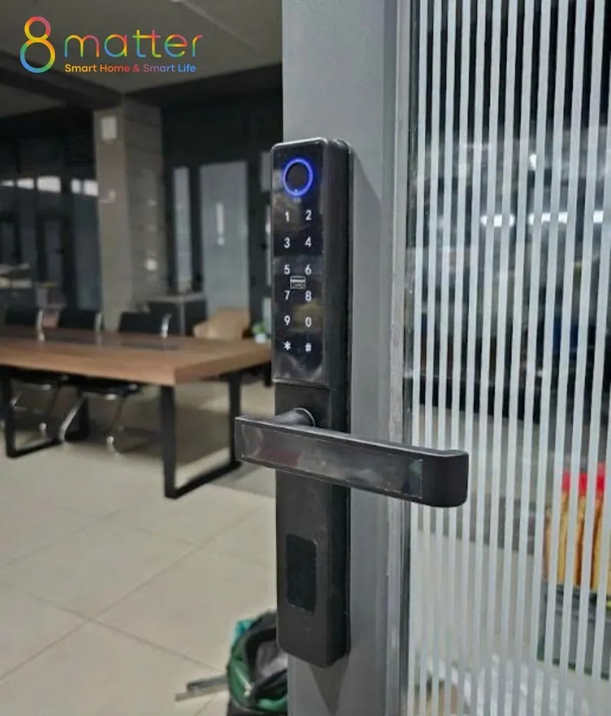 Khoá vân tay trên cửa kính sọc, phía trong là phòng họp bàn gỗ ghế