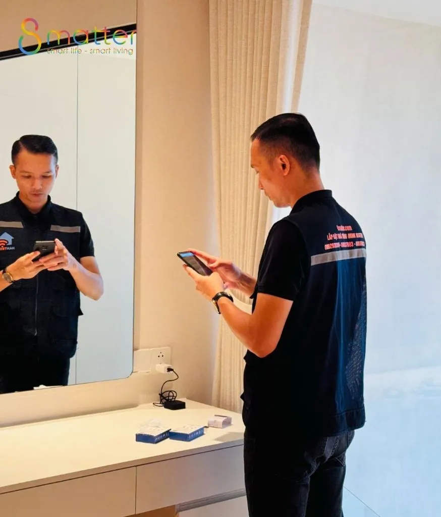 Hai kỹ thuật viên mặc áo đồng phục kiểm tra hệ thống trong phòng bằng điện thoại