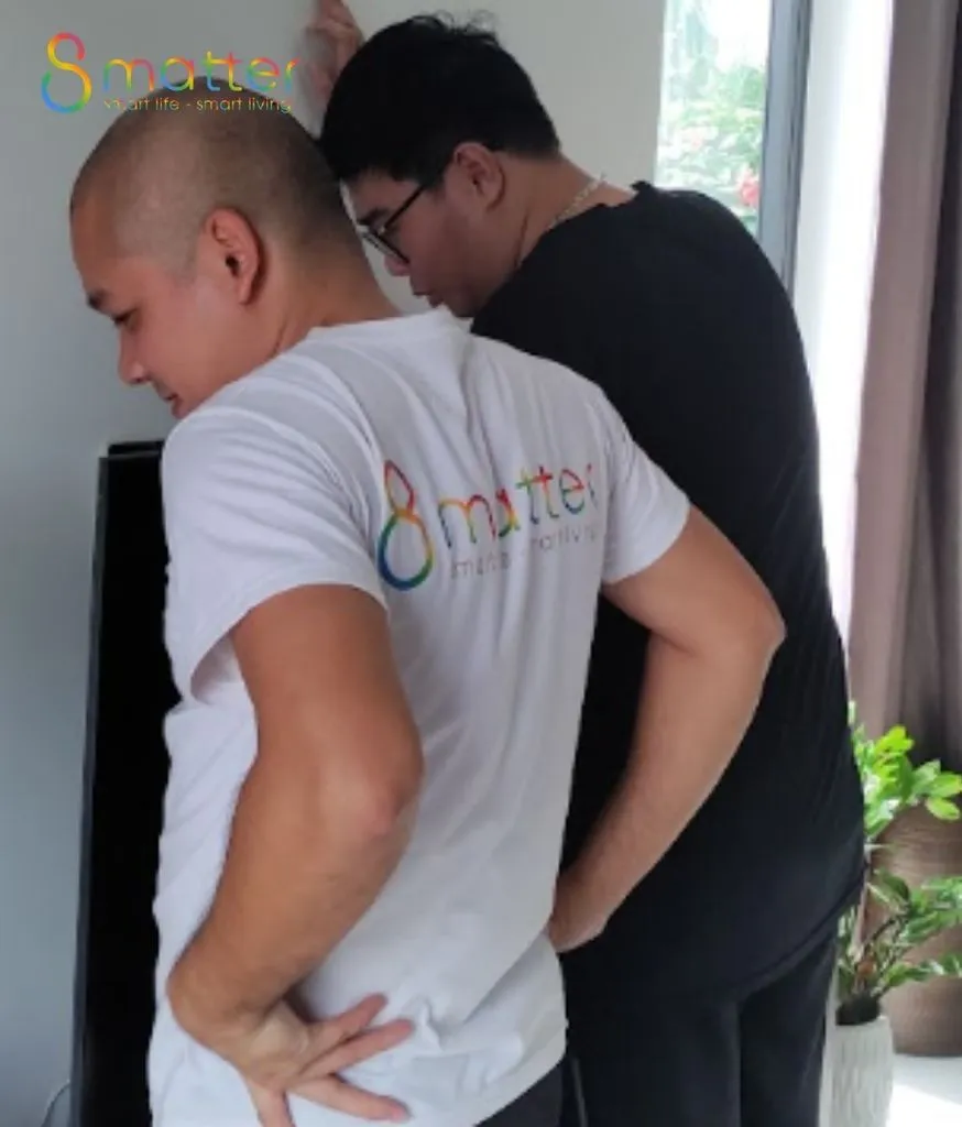 Hai người đàn ông đứng cạnh nhau, người áo trắng in logo quay lưng