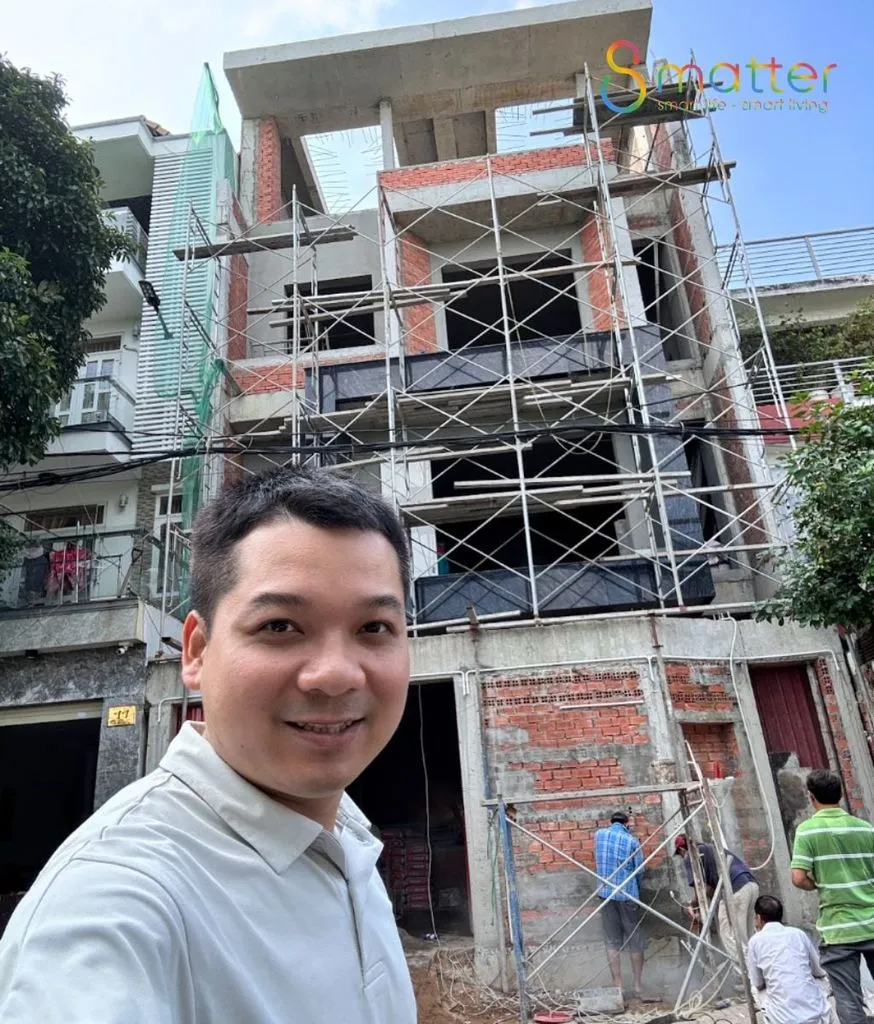 Nhân viên 8matter đứng chụp ảnh trước ngôi nhà đang xây có giàn giáo