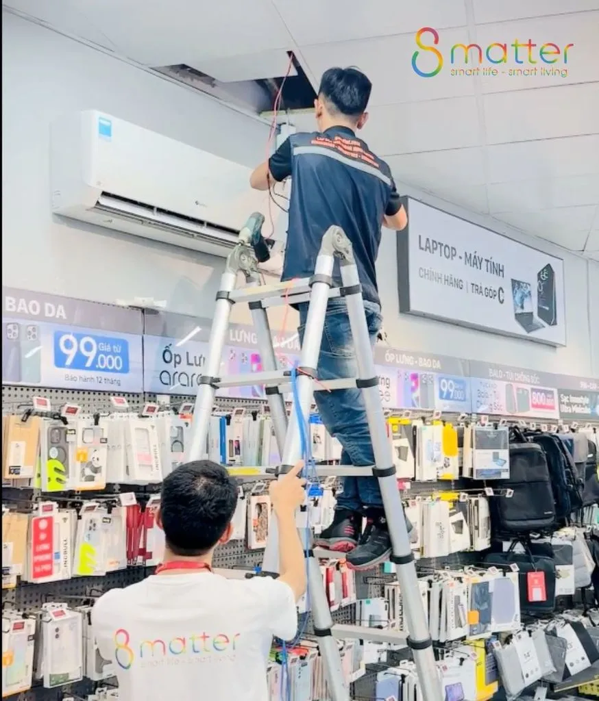 Nhân viên đứng trên thang lắp máy điều hoà bên trong cửa hàng
