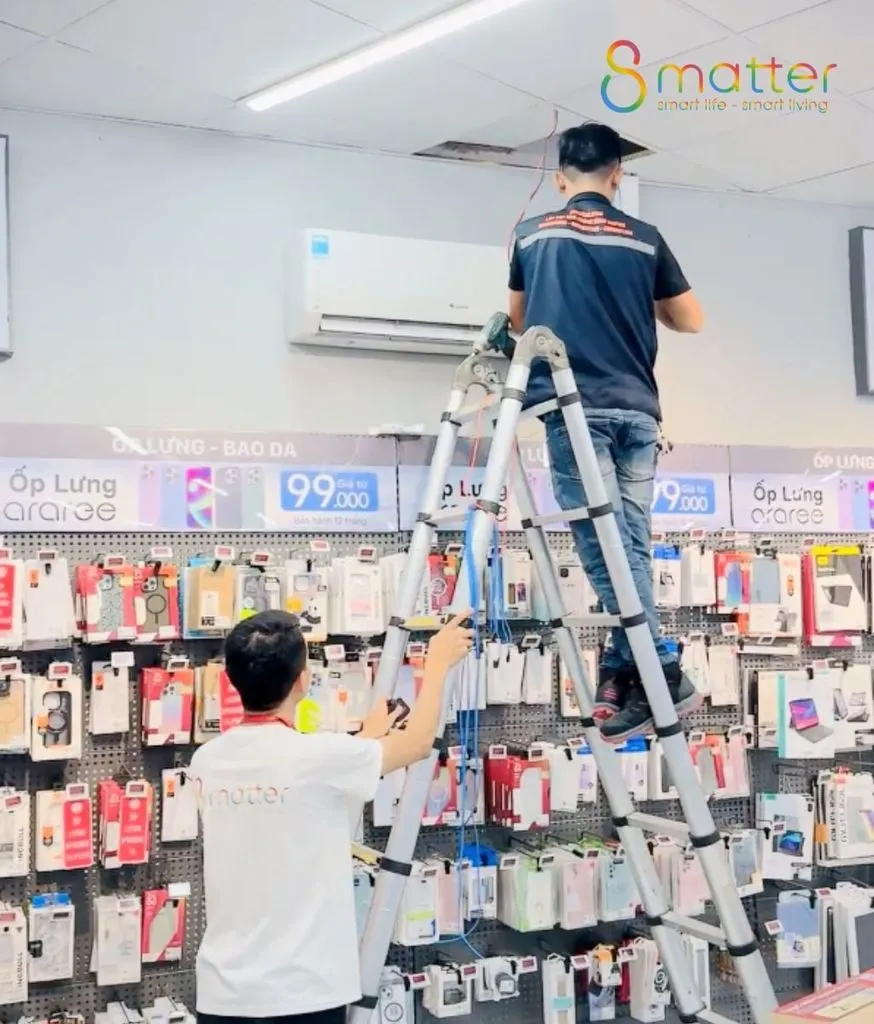 Nhân viên đứng trên thang lắp thiết bị lên trần bên trong cửa hàng