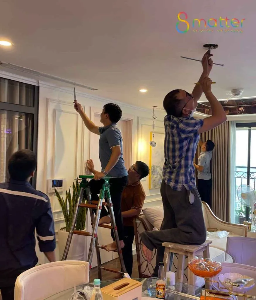 Nhóm người đang cùng nhau lắp bộ đèn trần trong phòng khách