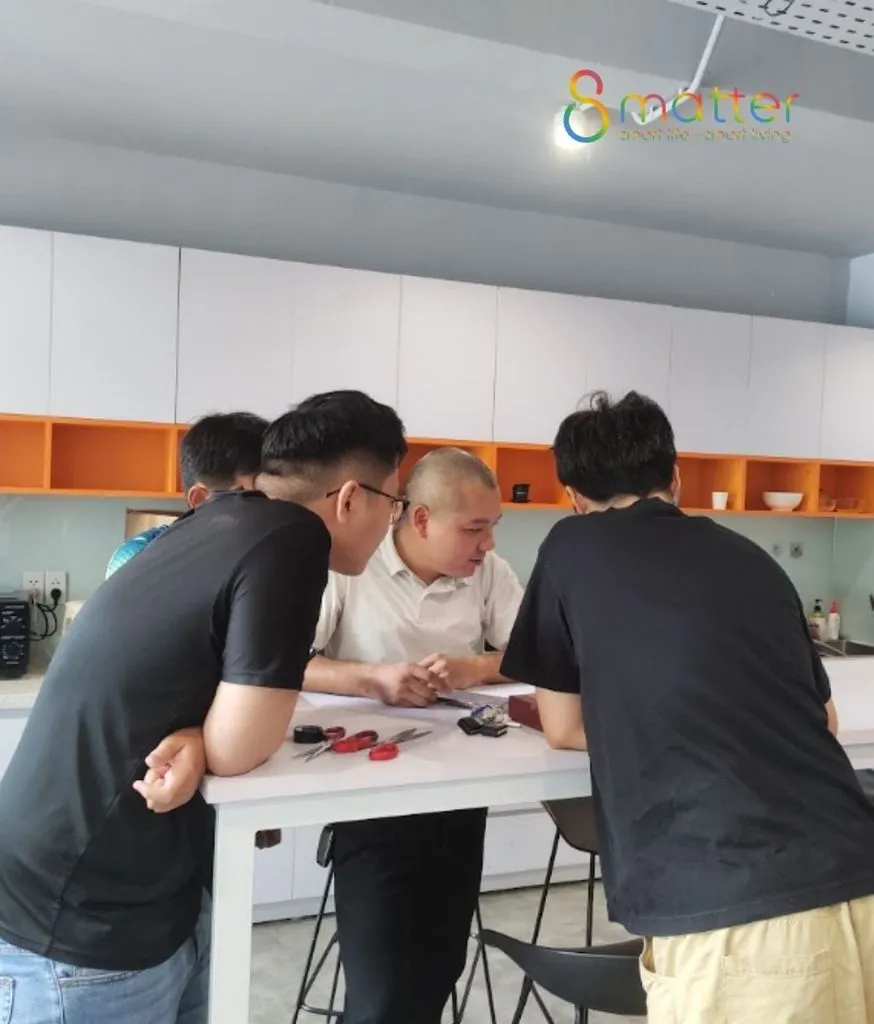 Nhóm nhân viên ngồi quanh bàn cùng xem các thiết bị trong showroom