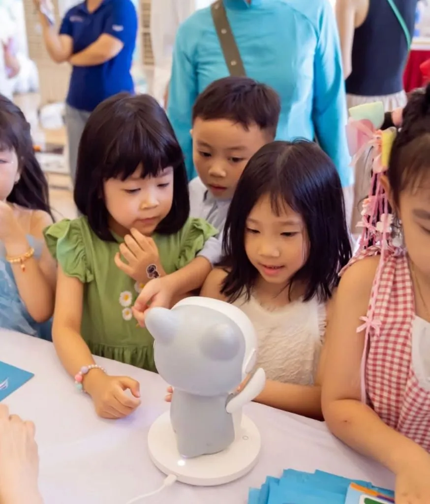 Nhóm trẻ ngồi quanh bàn cùng chơi với một robot Pika đặt ở giữa