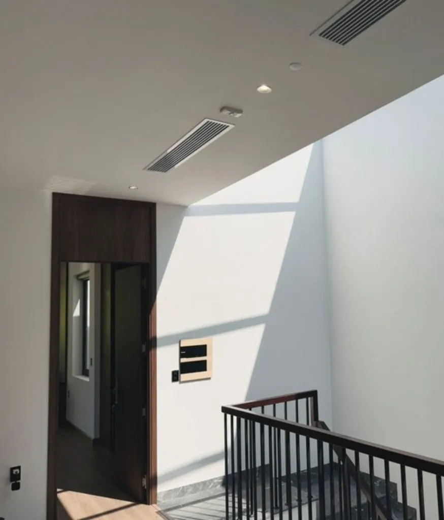 Góc trần và cầu thang, tường trắng gắn thiết bị điều khiển cạnh cửa gỗ