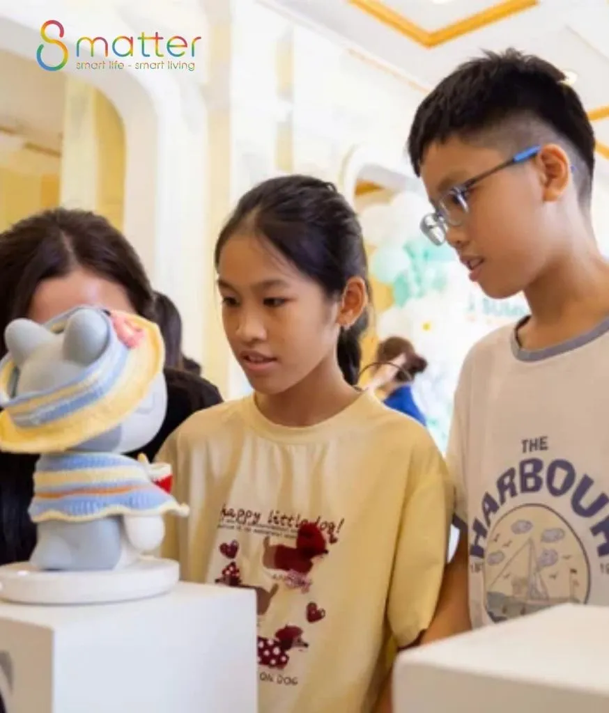 Hai trẻ em và một phụ nữ ngắm robot trắng đội mũ len