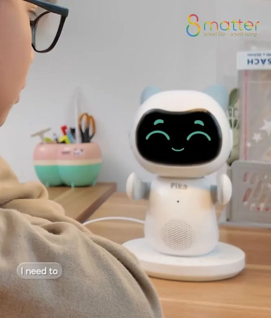 Robot Pika đứng trên mặt bàn, ngay bên cạnh là một chiếc hộp bút