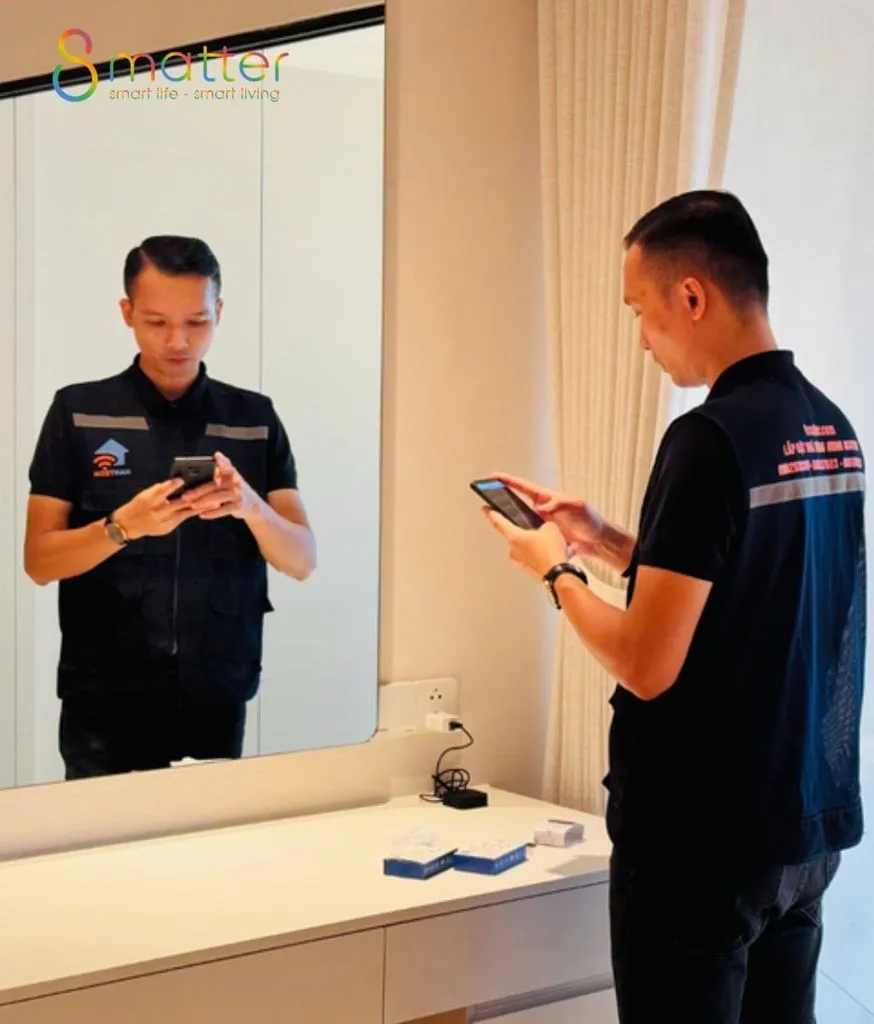 Nhân viên đồng phục đen cầm điện thoại khảo sát, hộp thiết bị trên bàn đá