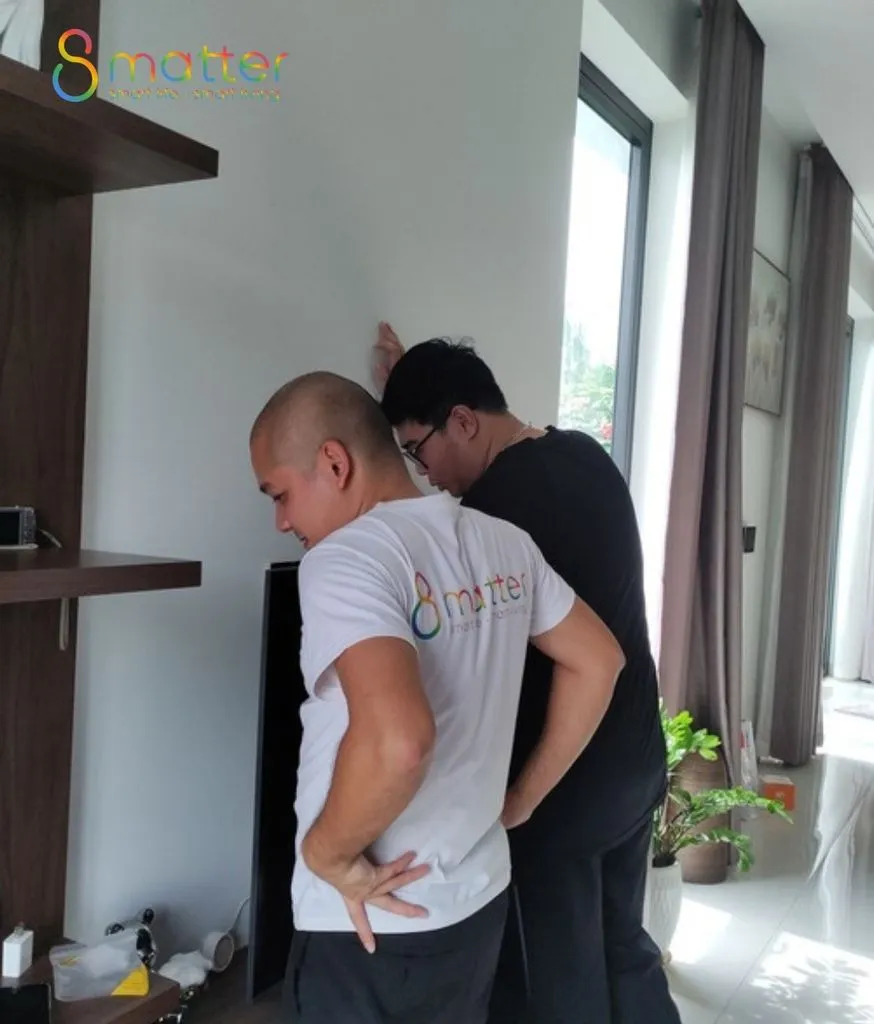 Hai người đàn ông áo trắng lắp thiết bị lên tường phòng khách cạnh cửa sổ